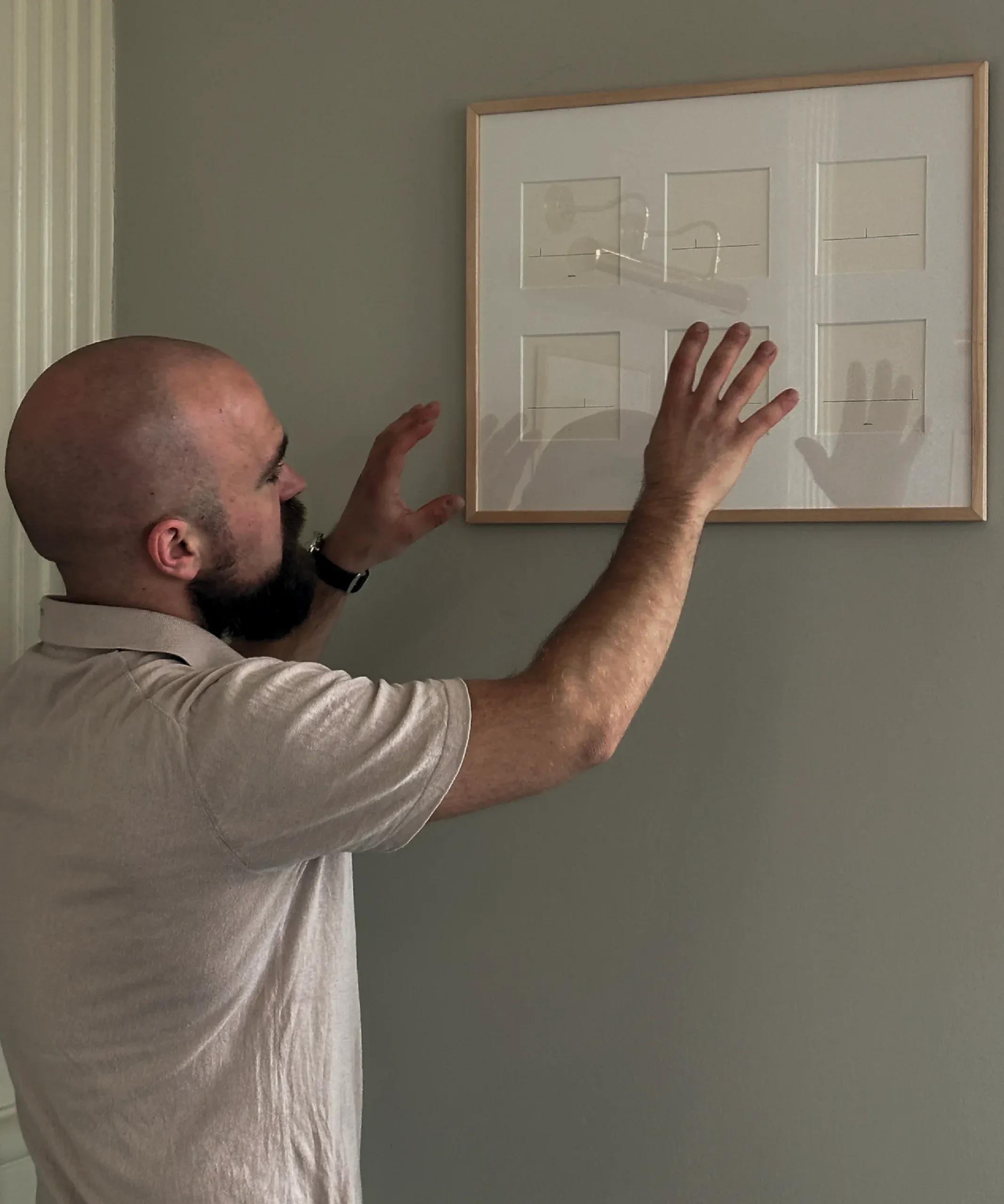 Framed drawings hung on a gallery wall, photographed at an angle.