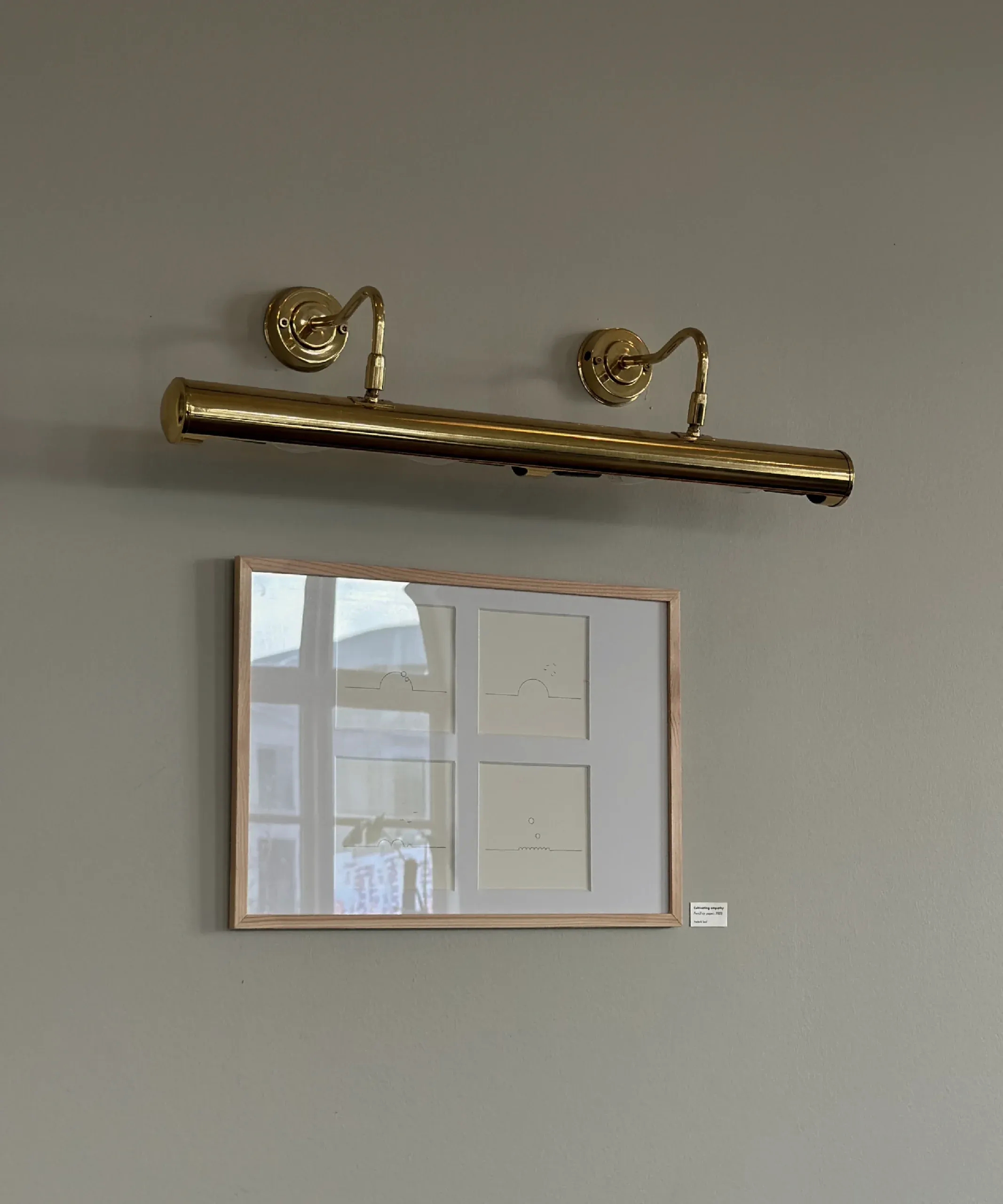 Framed line drawings on a gallery wall, view from across the room.